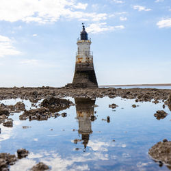 Lighthouse by sea against sky