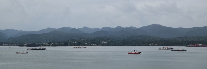 Boats in sea with mountains in background