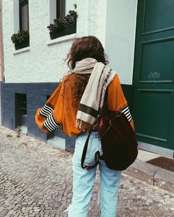 Rear view of woman standing in alley against building