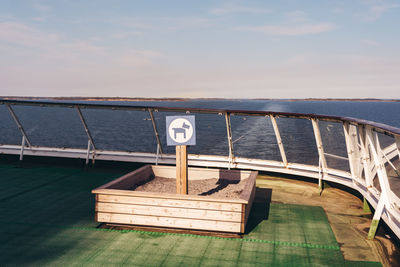 Information sign on railing by sea against sky