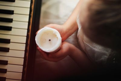 Close-up of woman holding candle by piano