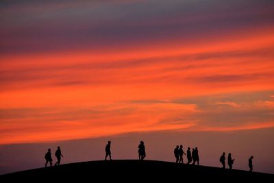 Silhouette people against orange sky
