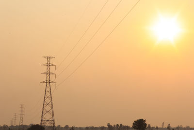 Low angle view of electricity pylon against sky during sunset