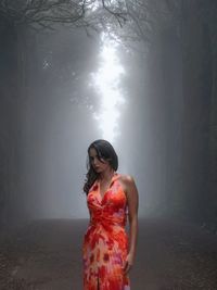 Portrait of young woman with arms outstretched standing at night