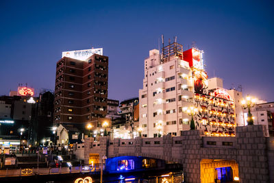 Low angle view of illuminated buildings against clear sky at night