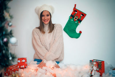 Portrait of smiling young woman holding camera at home