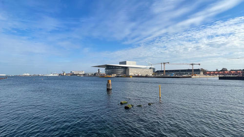 Buildings by sea against blue sky