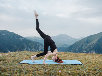 Woman with arms raised on mountain against sky