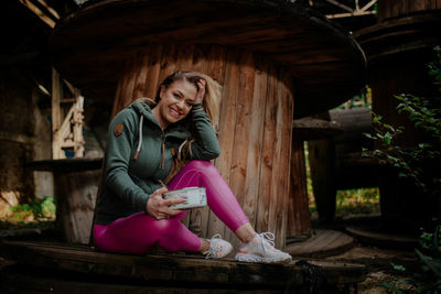 Full length of woman sitting on wood