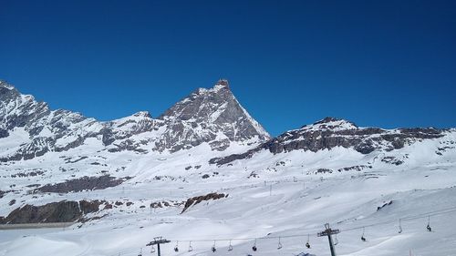 Scenic view of snowcapped mountains against clear blue sky