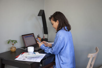 Woman sitting at desk and using phone