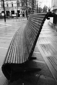 Empty bench by footpath in city