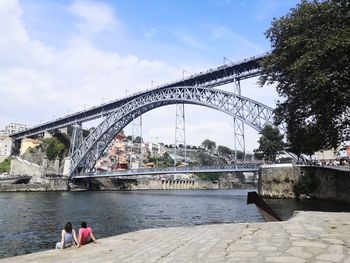 Bridge over river in city against sky