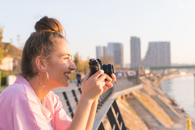 Woman photographing with camera in city