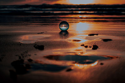 Surface level of beach against sky during sunset