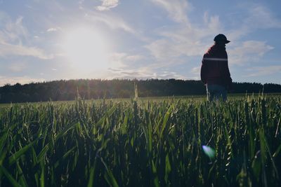 Low angle view of man standing on grassy field against sky on sunny day