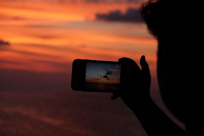 Silhouette person photographing at sunset