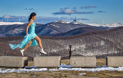 Woman standing on snow covered mountain against sky