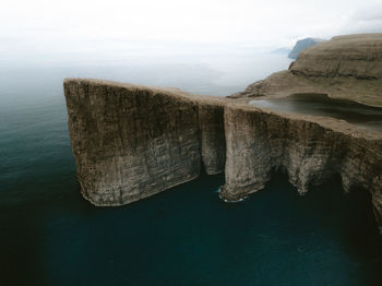 Rock formation in sea against sky