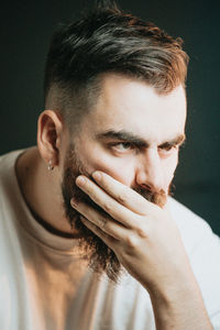 Close-up of young man looking away against black background