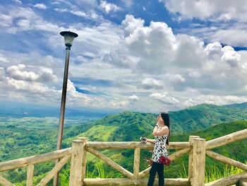 Woman standing by railing against mountain