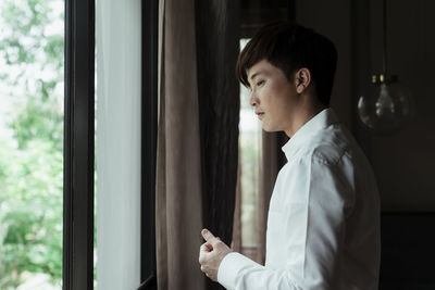 Side view of young man looking through window