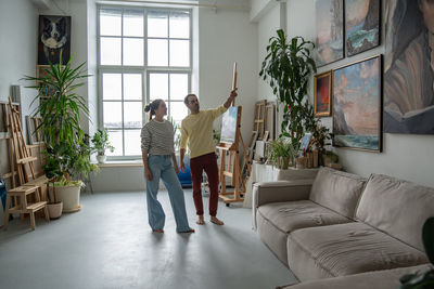 Rear view of young woman with arms raised standing at home