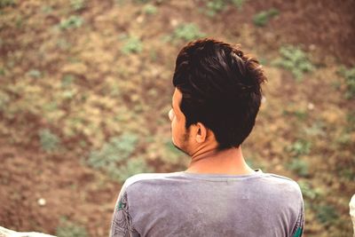 Rear view of young man looking away on land