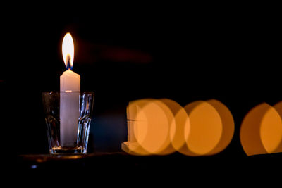 Close-up of illuminated candles on table in dark room