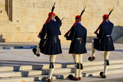 Rear view of women walking against wall