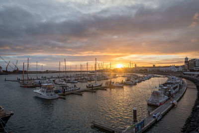 Boats moored at harbor during sunset