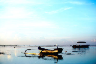 Fishing boat moored in sea against sky