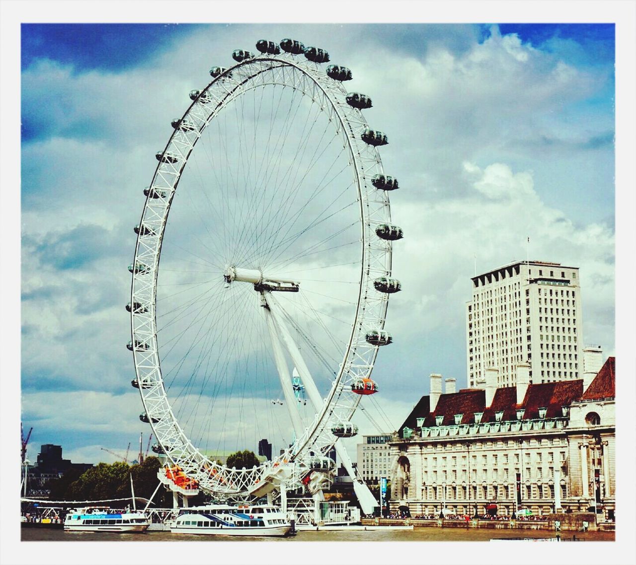 ferris wheel, amusement park, amusement park ride, arts culture and entertainment, built structure, architecture, sky, cloud - sky, millennium wheel, travel destinations, tourism, building exterior, city, low angle view, famous place, fun, travel, cloud, leisure activity, capital cities