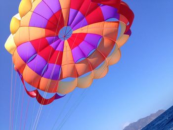 Low angle view of colorful parachute over sea against sky