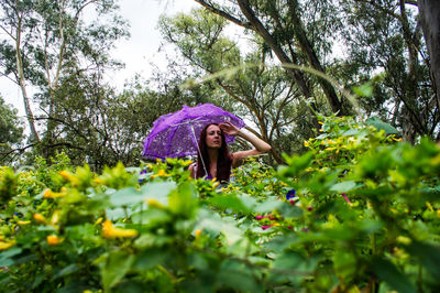 Woman standing by purple flowering plants