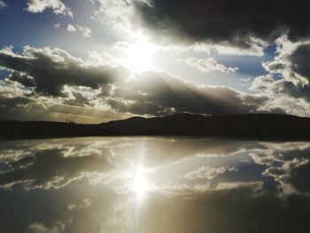 Sun streaming through clouds in sky during sunset