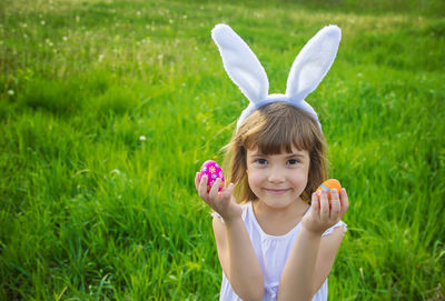 Midsection of woman playing with ball on grassy field