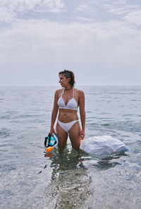 A young girl with diving goggles pulling trash out of the ocean. recycling concept