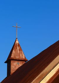 Low angle view of weather vane against blue sky