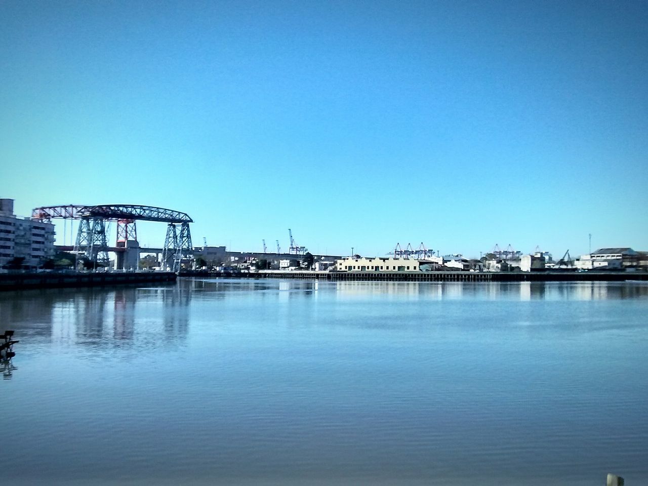 clear sky, copy space, architecture, built structure, building exterior, water, blue, waterfront, river, city, reflection, mid distance, cityscape, lake, outdoors, no people, bridge, day, residential structure, connection