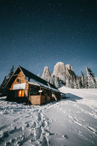 Houses by snowcapped mountain against sky at night