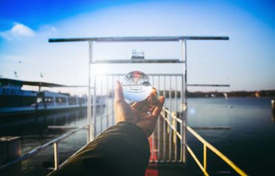 Close-up of hand holding railing against river in city