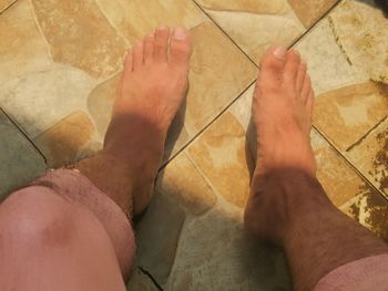Low section of man standing on tiled floor