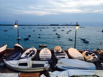 Boats moored at harbor against sky