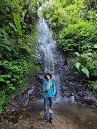 Full length of woman standing on rock in forest