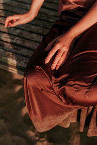 Low section of woman sitting on bench outdoors