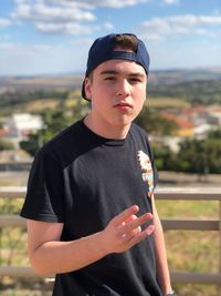 Portrait of young teenage boy gesturing while standing outdoors