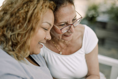 Smiling young female caregiver sitting with senior woman at retirement home