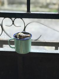 Close-up of coffee cup on window sill