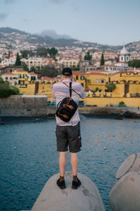 Rear view of man standing on tetrapod looking at townscape